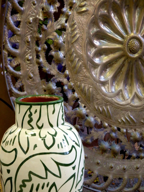 cream colored vase with green decorative pattern and large brass platter